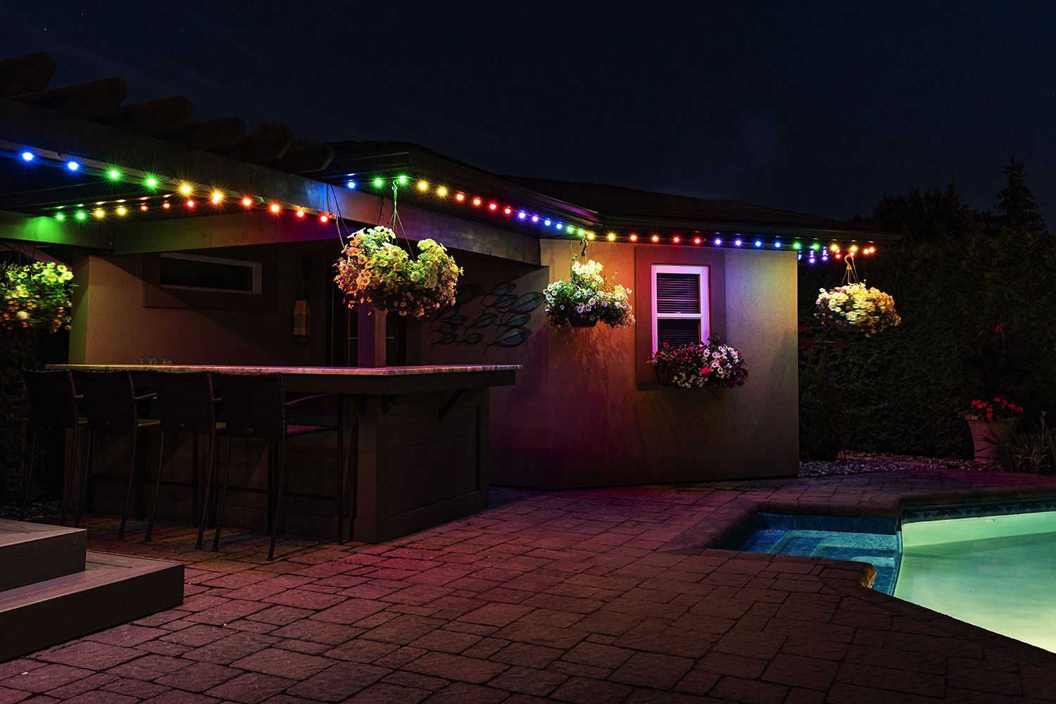 Backyard patio lit up with colorful permanent lighting for entertaining